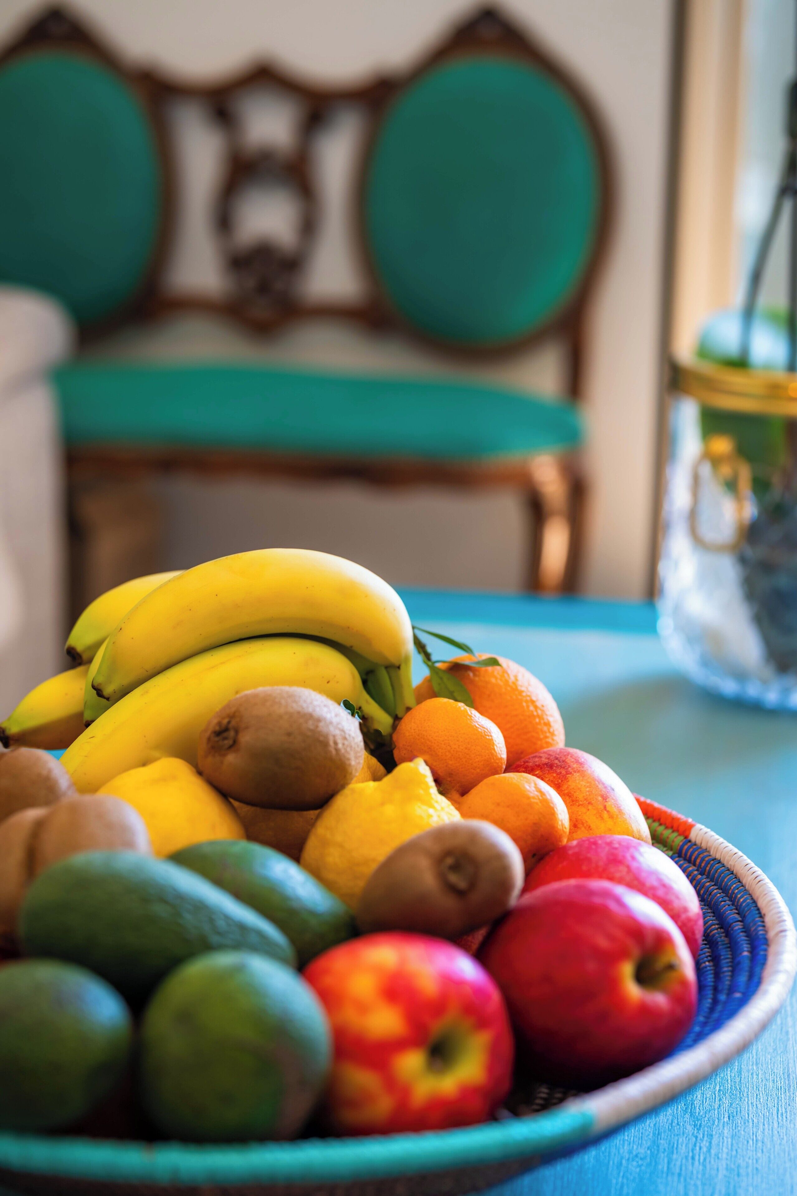 A bowl of fruit including bananas, kiwis, oranges, apples, and limes.