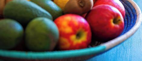 A bowl of fruit including bananas, kiwis, oranges, apples, and limes.