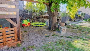 Ein hölzernes Spielhäuschen mit Schaukel und einem Baum im Hintergrund.