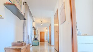 Ein geräumiger Flur mit einer hölzernen Sitzbank, einem an der Wand befestigten Regal mit Spielzeug und einer Tür zu einem Zimmer.