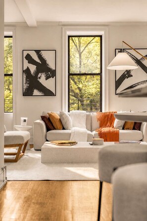 Una sala de estar moderna con un sofá blanco, una mesa de centro y obras de arte en las paredes.