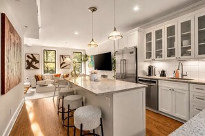 A modern kitchen with a large island, stainless steel appliances, and a bar area with stools. - Madison I by StayHaus | Full-floor Flatiron 2BR (New York)