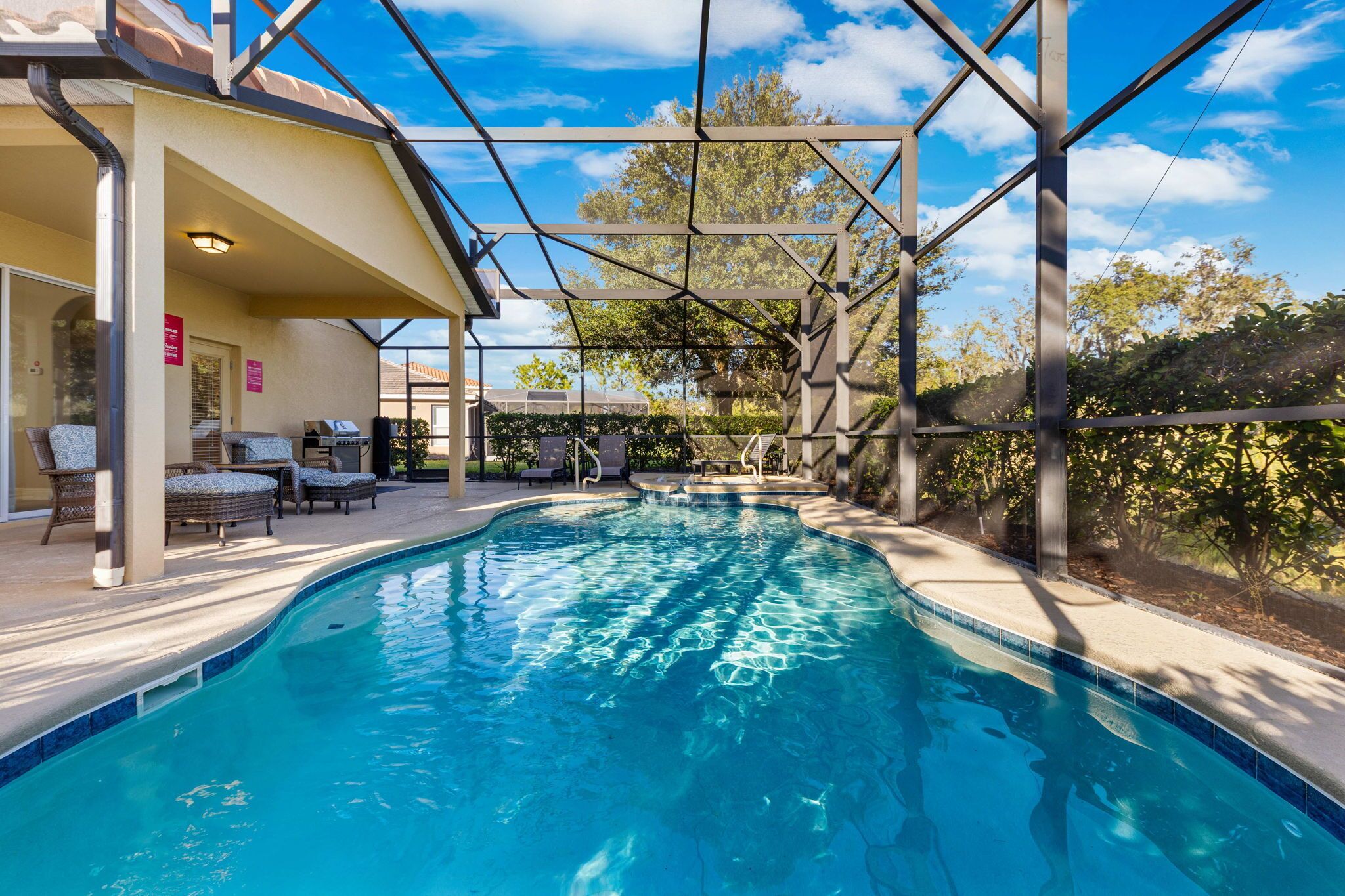 A swimming pool with a covered area, lounge chairs, and a pergola structure.