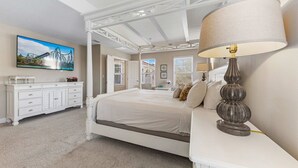 A bedroom with a four-poster bed, a bedside lamp, a dresser, and a painting on the wall. - 4163 Oak Tree Drive (Davenport)
