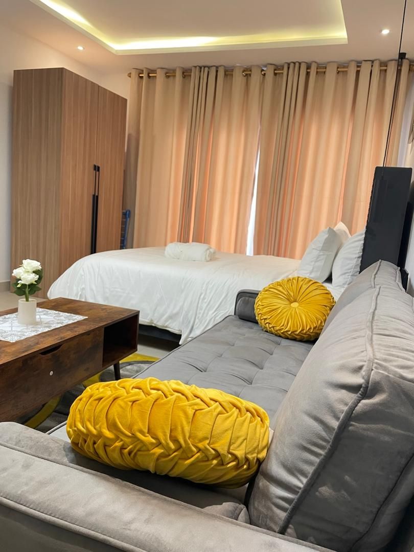 Ein modernes Hotelzimmer mit einem Bett, einer Couch und einem Holznachttisch.
