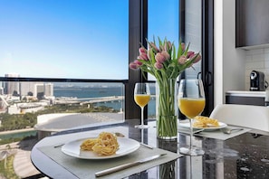 Une table Ă manger avec une assiette de pĂątes, deux verres de jus dâorange et un vase de tulipes.
