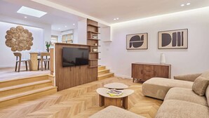 A modern living room with a flat-screen TV, wooden furniture, and artwork on the walls. - Charming apartment - Canal Saint-Martin (Paris)