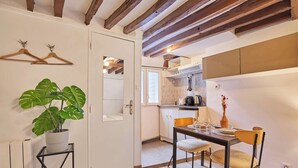 Un coin repas avec une table dressée pour deux personnes, une plante en pot et des poutres en bois au plafond.