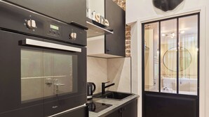 A modern kitchen with a built-in oven, a coffee maker, and a sink. - Charming Apartment - Paris Pere Lachaise (Paris)
