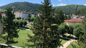 Una zona residenziale con un’area giochi, case e una collina boscosa sullo sfondo.