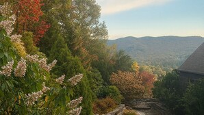 A natural landscape with a stone bridge over a stream, surrounded by trees with autumn foliage. - Sapphire Retreat • Stylish 1BR Suite + Hot Tub, Views, Ski Hill & Outdoor Living (Sapphire)