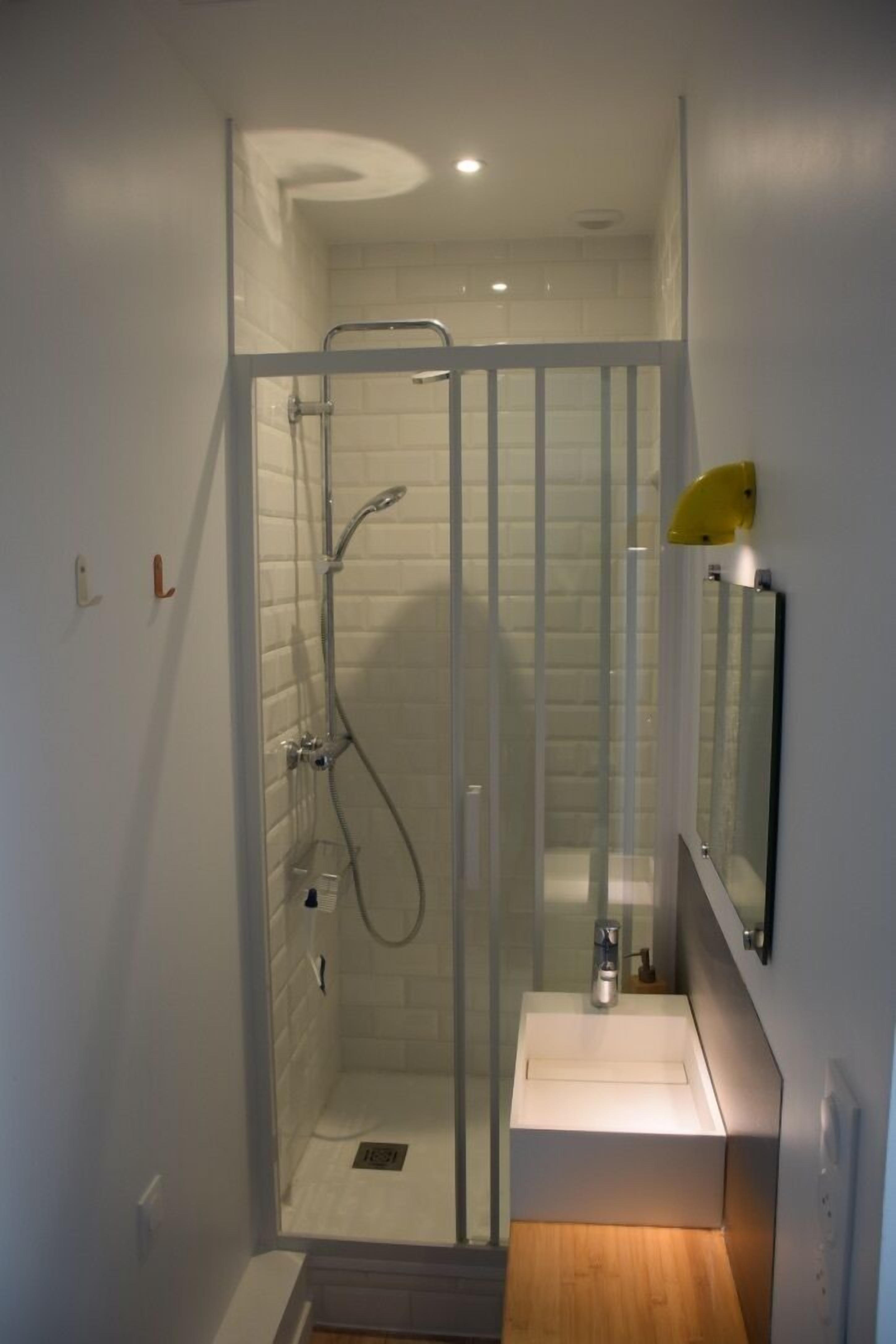 A modern bathroom with a glass-enclosed shower, a white sink, and a mirror.