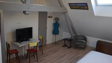 Una habitación pequeña y funcional con cama, escritorio con televisor y una silla.