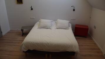 A bedroom with a bed, a bench, a red cabinet, and a wall-mounted light fixture.