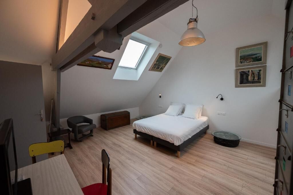 Een slaapkamer met dakraam, een bed, een bureau en een stoel.