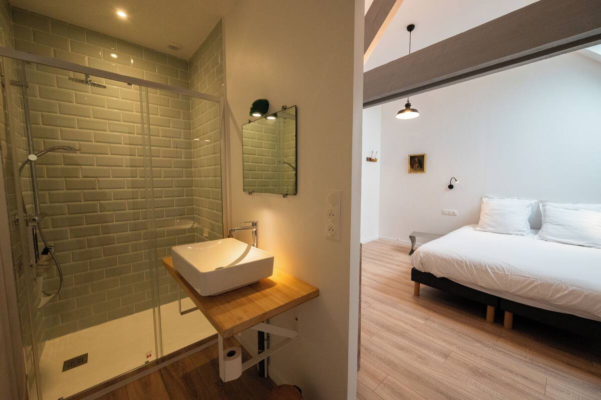 A modern bathroom with a glass shower enclosure, a wooden vanity with a white sink, and a large mirror.
