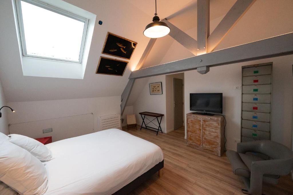 A bedroom with a bed, a TV, a desk, and a chair.