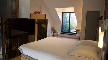 Une chambre avec un grand lit, une télévision, une chaise et une fenêtre.