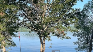 A lakeside deck with a picnic table, a small boat, and a flagpole. - 4BR Waterfront Escape w/Woodstoves & Large Dock (Algonquin Highlands)