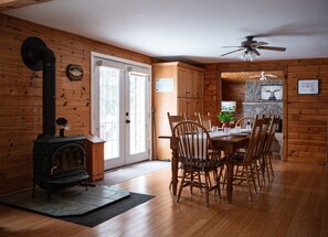A wooden interior with a dining table and chairs, a stove, and a ceiling fan.