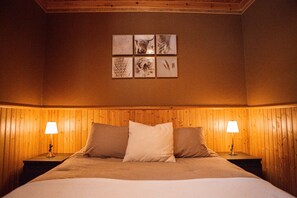 A bedroom with a wooden headboard, two bedside lamps, and a bed with three pillows.