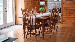A wooden dining room with a table and chairs, a potted plant, and a fireplace in the background. - 4BR Waterfront Escape w/Woodstoves & Large Dock (Algonquin Highlands)