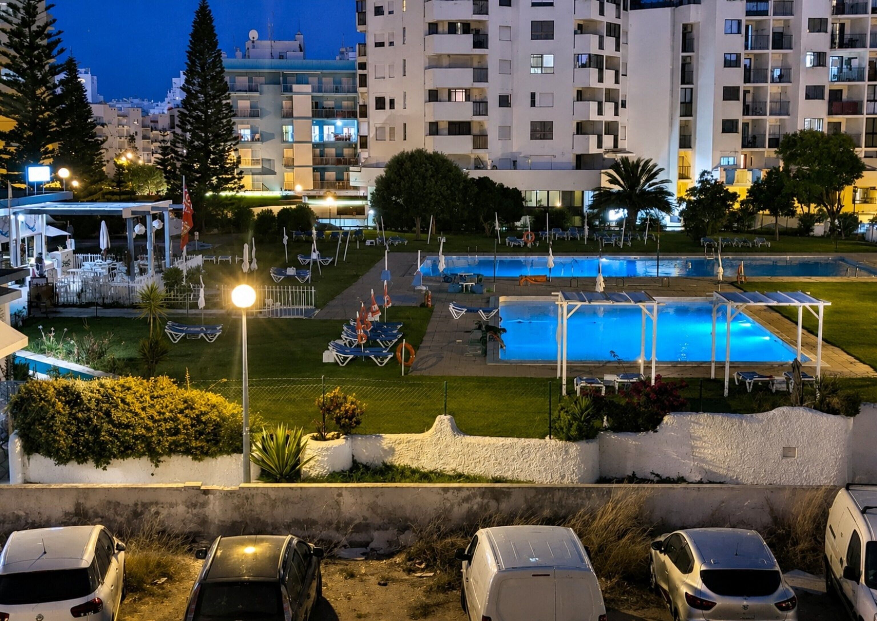 A residential area with a swimming pool, lounge chairs, and a gazebo.