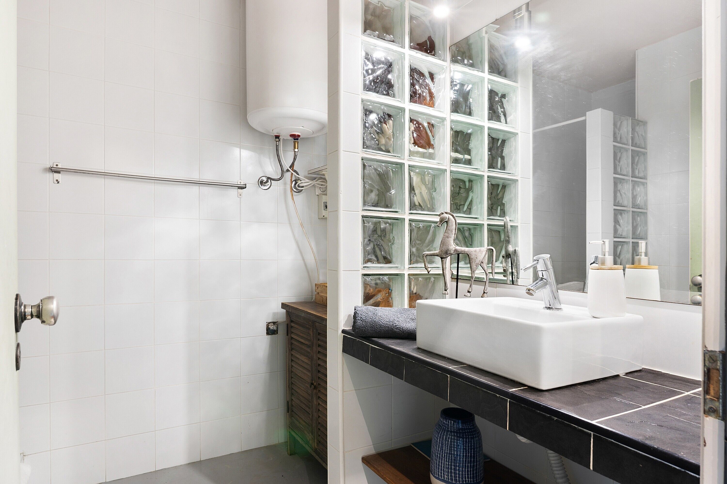 A bathroom with a white sink, a glass display cabinet, and a shower area.