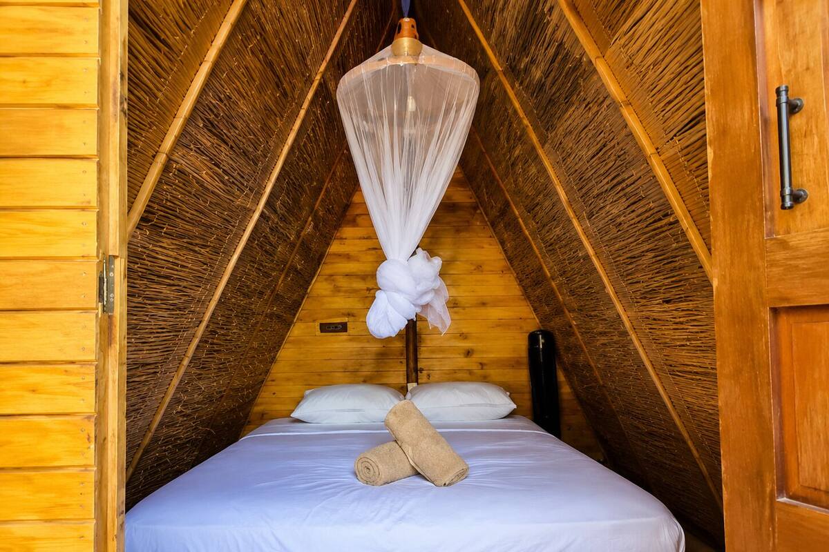 Une pièce triangulaire avec un lit, une moustiquaire et des murs en bois.