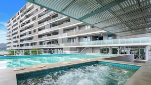A modern hotel with a large outdoor pool, multiple balconies, and a rooftop terrace. - Marina Vista—Waterfront Stay near Dining & Markets (Cairns)