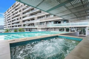 Ein modernes Hotel mit großem Außenpool, mehreren Balkonen und einer Dachterrasse.