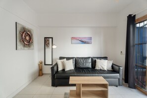 Un salon moderne avec un canapé en cuir noir, une table basse en bois et des œuvres d’art accrochées aux murs.