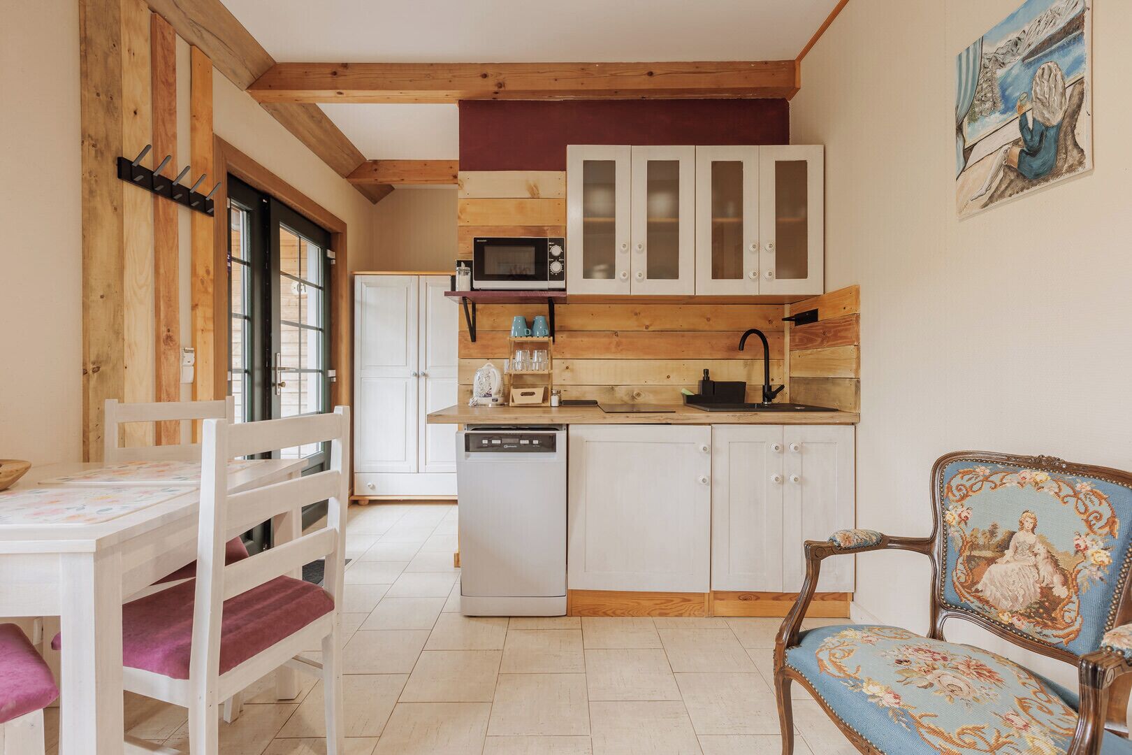 A compact kitchen with wooden beams, white cabinets, a microwave, and a dishwasher.