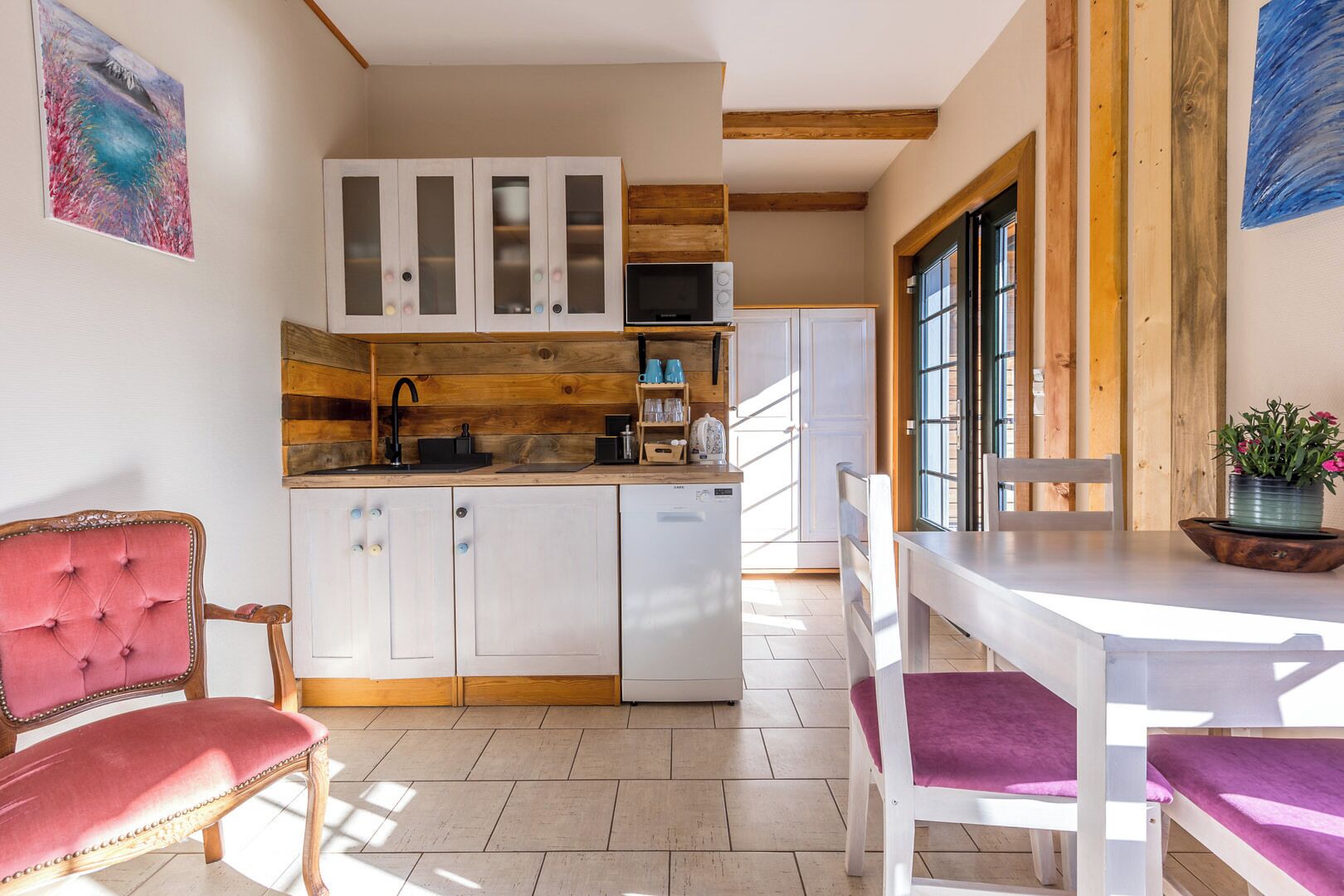 A modern kitchen with white cabinets, a wooden countertop, and a dining area with a white table and purple chairs.