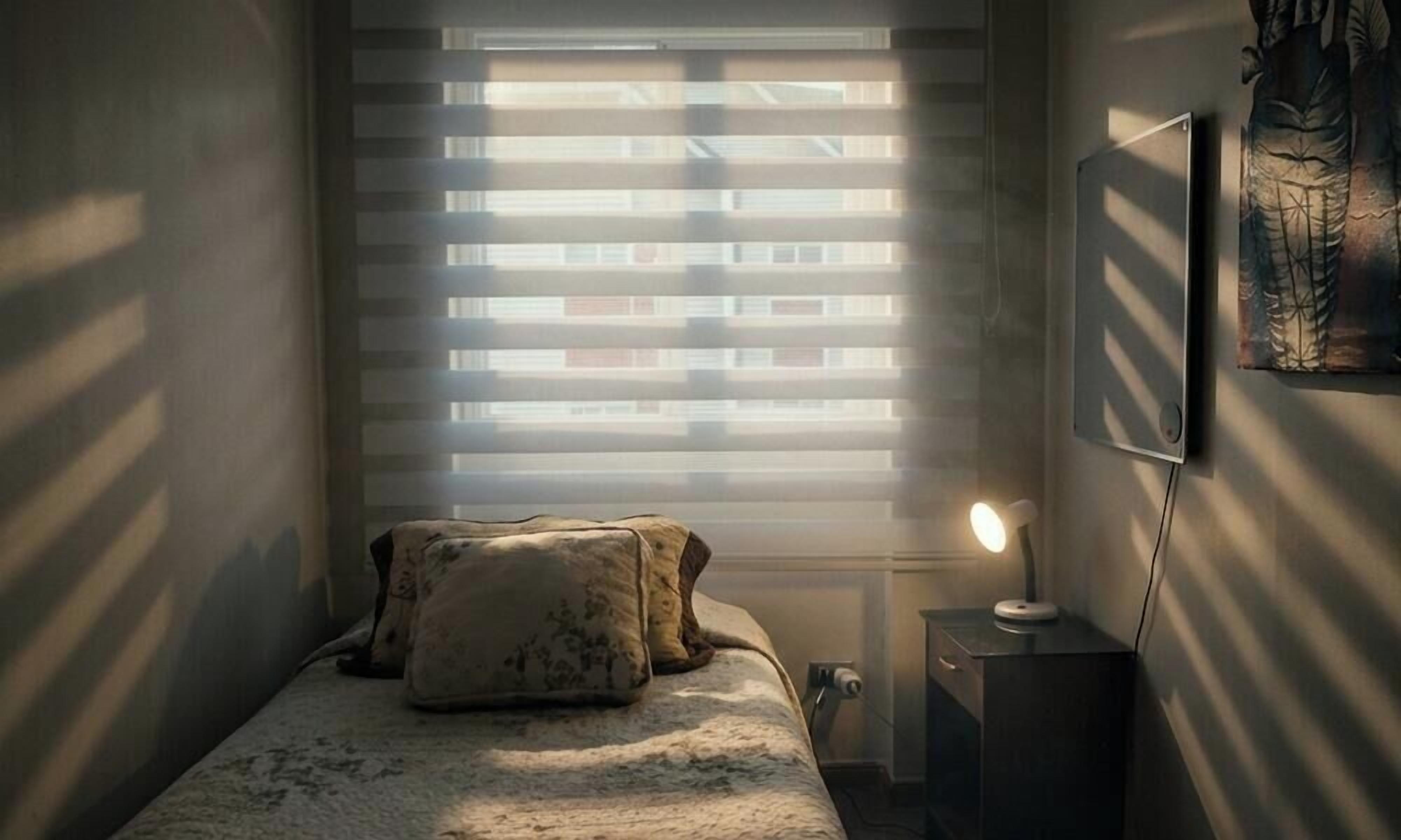 A bedroom with a bed, a nightstand, a lamp, and a wall-mounted artwork.