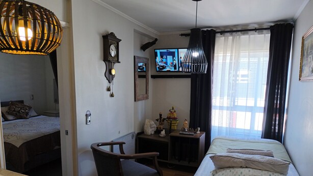 Une chambre d’hôtel comprenant un lit, un bureau avec une chaise, un téléviseur et un luminaire suspendu.