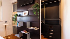 A modern room with a built-in shelving unit, a small table, and a black wardrobe. - notaMI - Settimo Cielo - San Cristoforo (Milan)