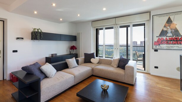 A modern living room with a sectional sofa, a coffee table, and a large window with a city view. - notaMI - Settimo Cielo - San Cristoforo (Milan)