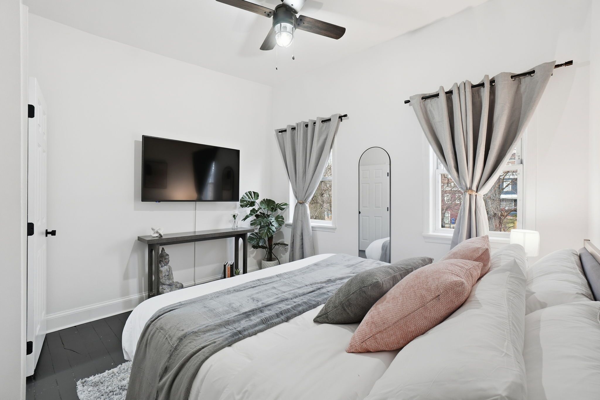 Une chambre moderne avec un lit, une télévision, une plante et un ventilateur de plafond.