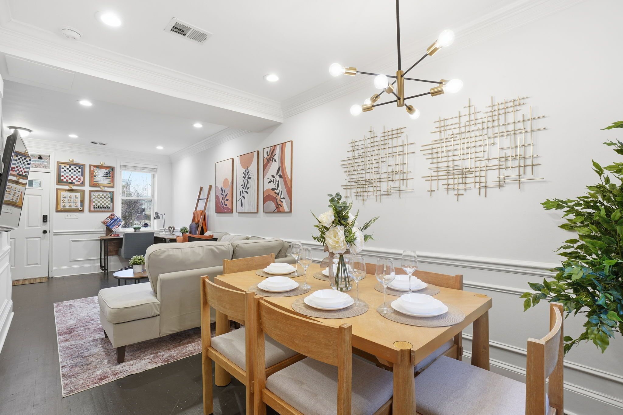 Un coin repas avec une table en bois dressée pour quatre personnes, entourée de chaises rembourrées.