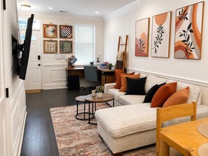 A living room with a sofa, coffee table, and artwork on the wall. - NEW! Charming 3BR/BA home, Private Prkng or Patio, Near Convention Center, Metro (Washington)
