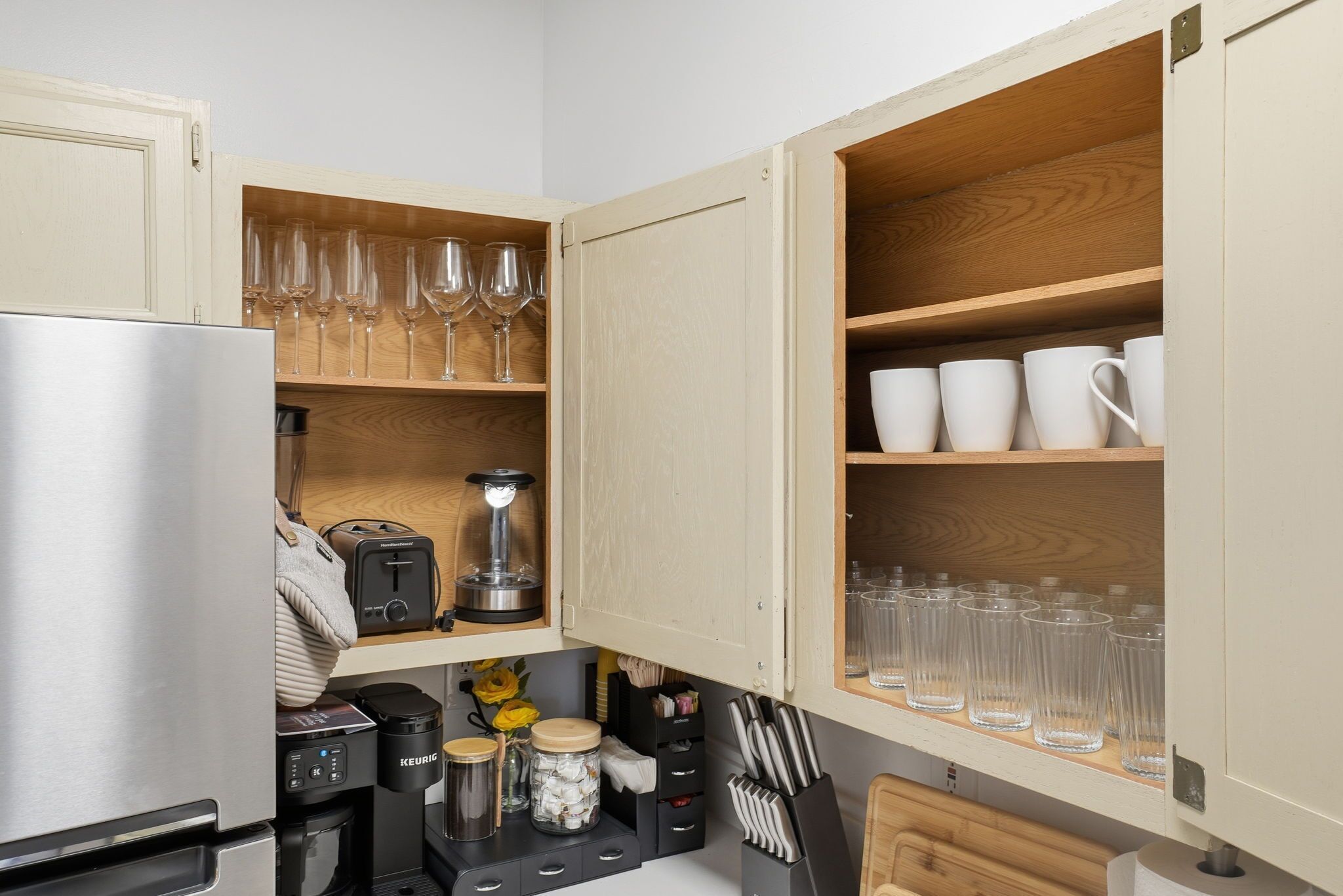 Une cuisine dotée de meubles en bois, d’un réfrigérateur en acier inoxydable, d’une machine à café et de divers ustensiles de cuisine.