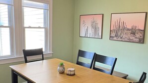 Una sala da pranzo con un tavolo in legno, sedie, una panca, un lampadario e due quadri appesi al muro.