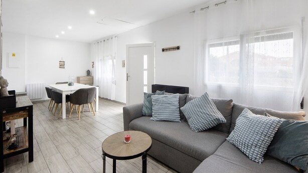 Ein modernes Wohnzimmer mit einer Couch, einem Esstisch und einem kleinen runden Tisch.