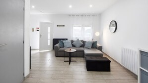 Ein modernes Wohnzimmer mit einem grauen Sofa, einem kleinen runden Tisch und einem schwarzen Hocker.