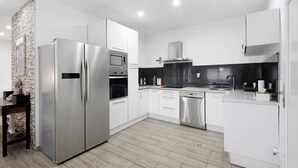 Eine moderne Küche mit Edelstahlgeräten, weißen Schränken und Holzboden.