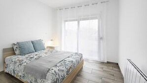 Ein Schlafzimmer mit Bett, Vorhängen, einem Nachttisch und einer Heizung.