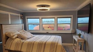 A bedroom with a bed, a window with a view, a ceiling light, and a TV on the wall. - Waterfront Dream Home in Bradenton Full of Amenities (Bradenton)