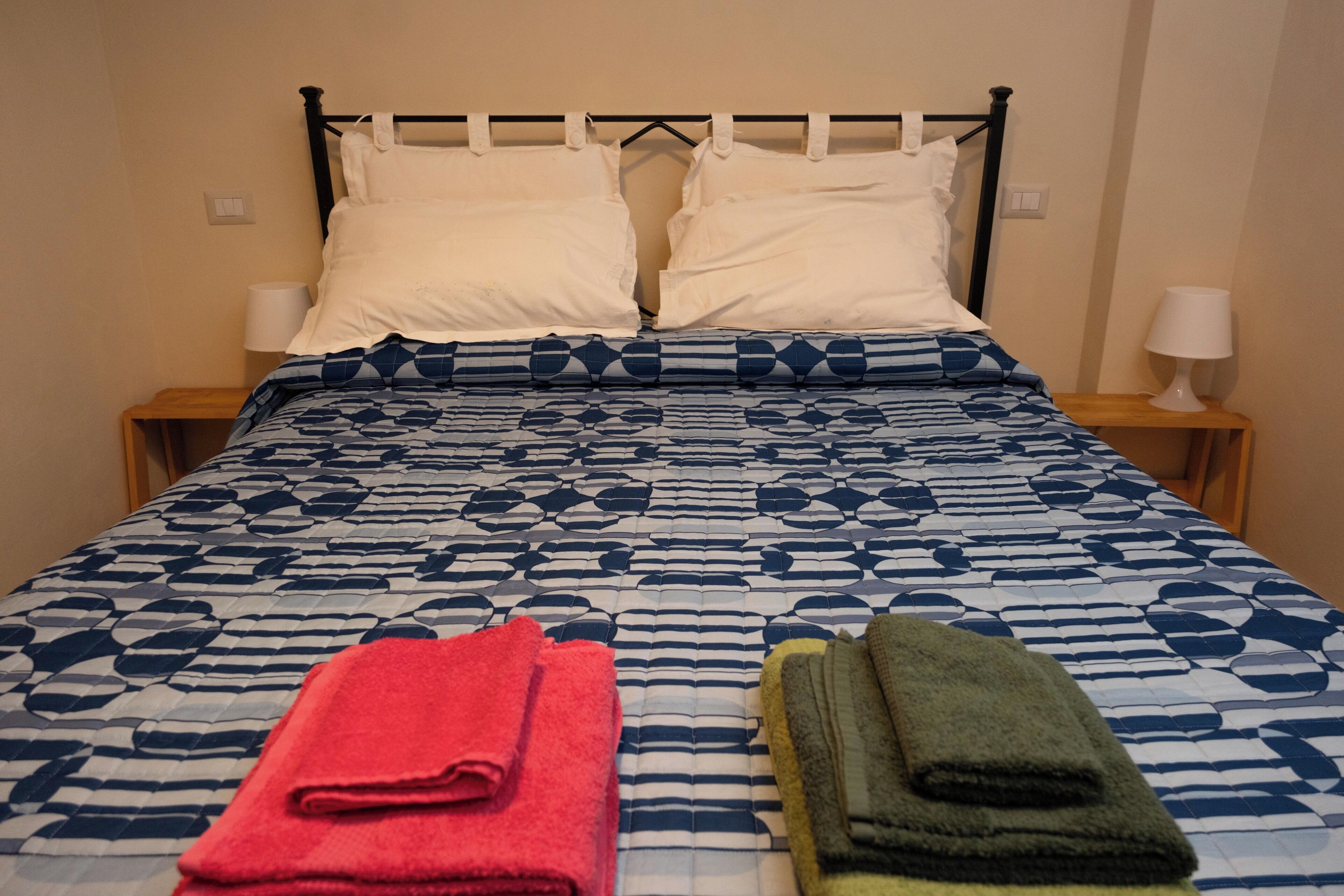 Un lit avec une couvre-lit à motifs, deux oreillers et deux tables de chevet avec des lampes.