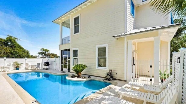 A two-story house with a swimming pool, white exterior, and a covered patio area. - Kiva's Jewel - Guest House (Gulf Shores)